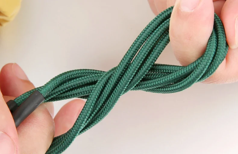 Person holding a green nylon braided 3-in-1 USB Charging Cable twisted for storage.